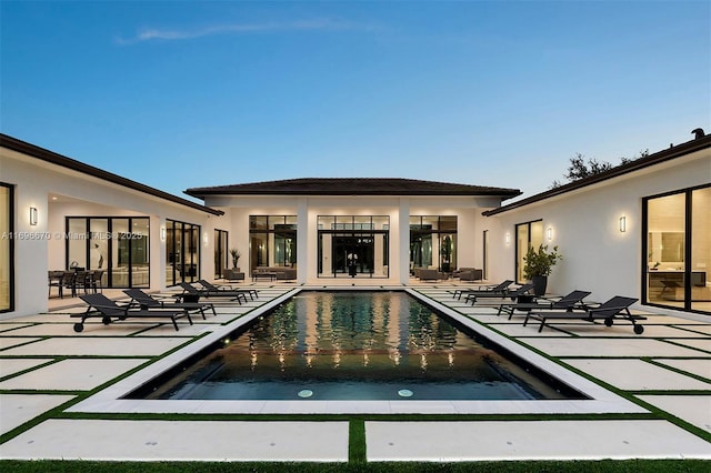 pool at dusk featuring a patio area