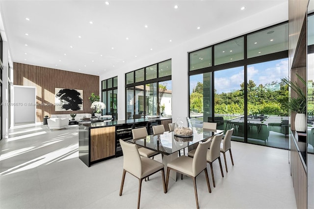 dining room featuring a high ceiling, plenty of natural light, and wood walls