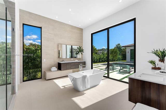 bathroom featuring a tub to relax in, vanity, and tile walls