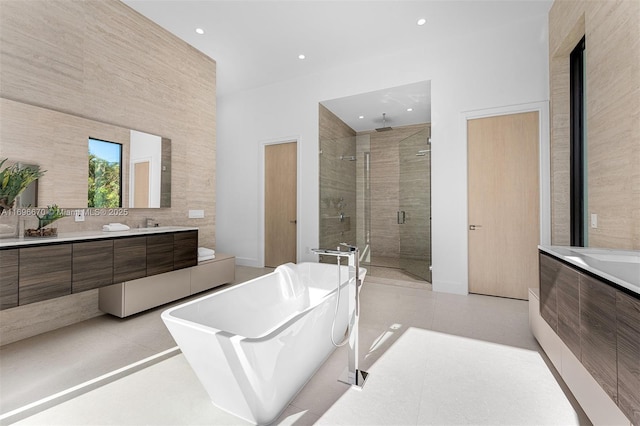 bathroom with tile patterned flooring, vanity, separate shower and tub, and tile walls