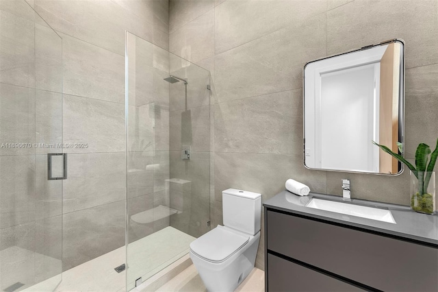 bathroom with vanity, toilet, a shower with door, and tile walls