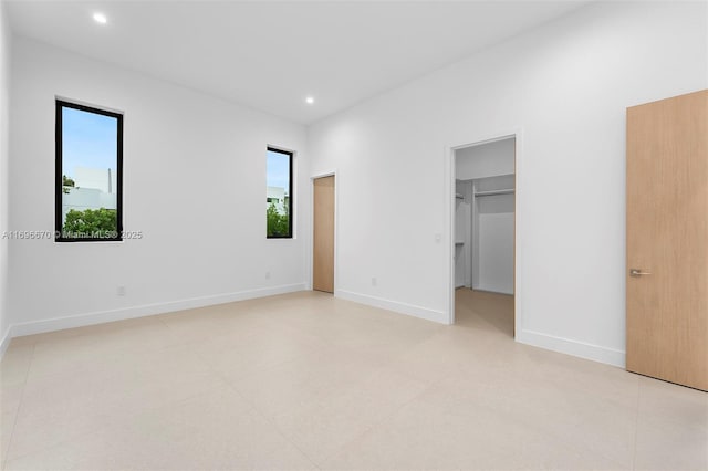 unfurnished bedroom featuring a closet, a spacious closet, and multiple windows