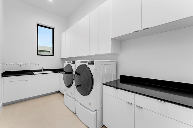 laundry area featuring washing machine and clothes dryer, cabinets, and sink