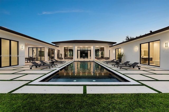 pool at dusk featuring a patio