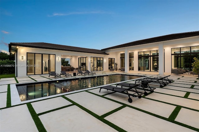 pool at dusk featuring a patio