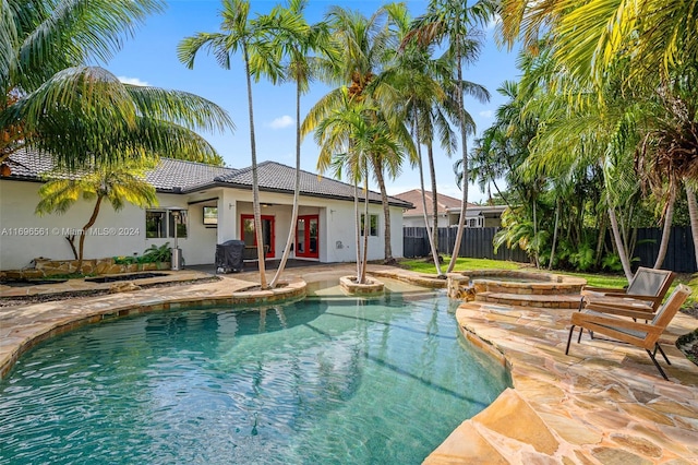 view of swimming pool with ceiling fan, french doors, a patio, and a jacuzzi