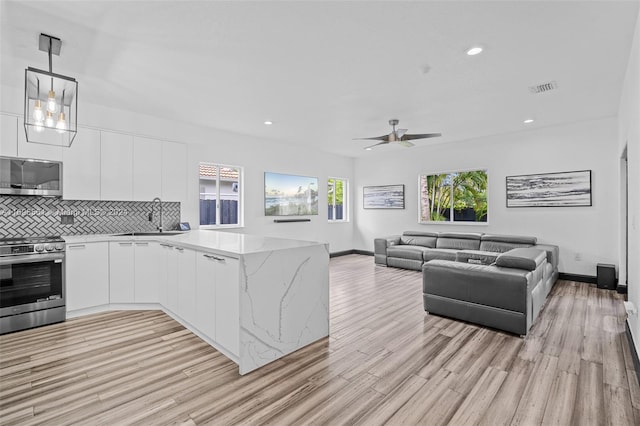 kitchen with pendant lighting, white cabinets, sink, kitchen peninsula, and stainless steel appliances