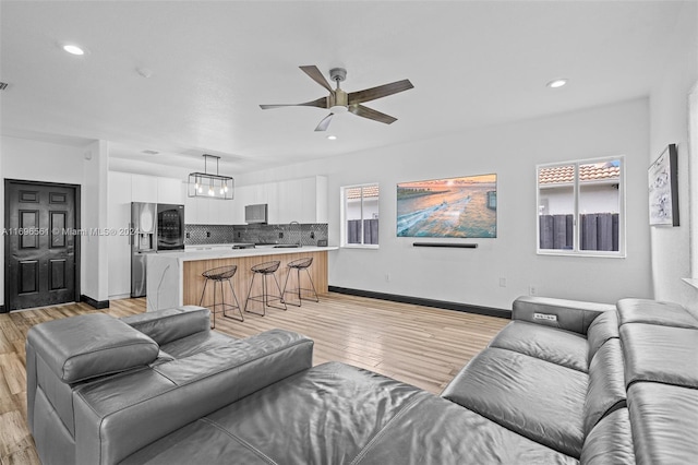 living room featuring ceiling fan with notable chandelier and light hardwood / wood-style flooring