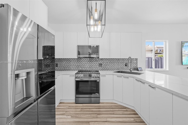 kitchen with decorative light fixtures, white cabinetry, and appliances with stainless steel finishes