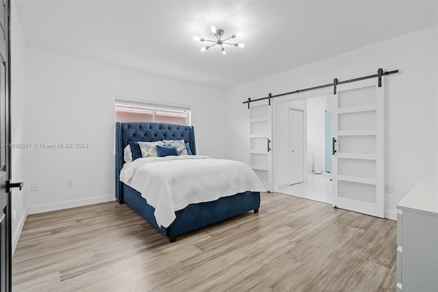 bedroom featuring a barn door, an inviting chandelier, and light wood-type flooring