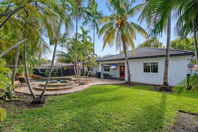 rear view of property featuring an in ground hot tub, a patio area, and a lawn