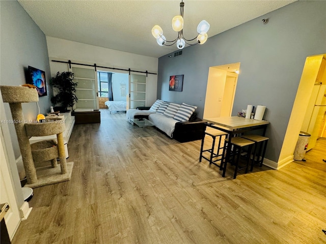 living room with a chandelier, hardwood / wood-style floors, a barn door, and a textured ceiling