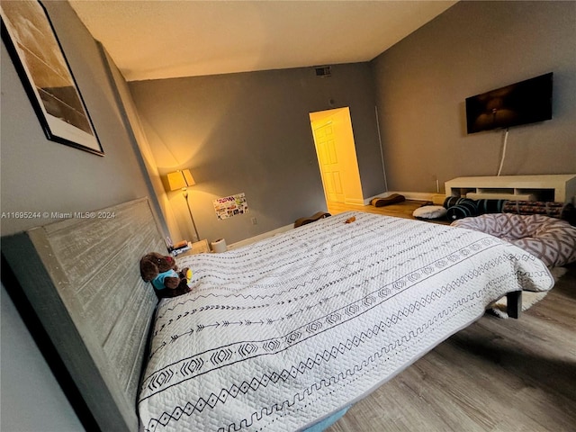 bedroom featuring wood-type flooring and vaulted ceiling