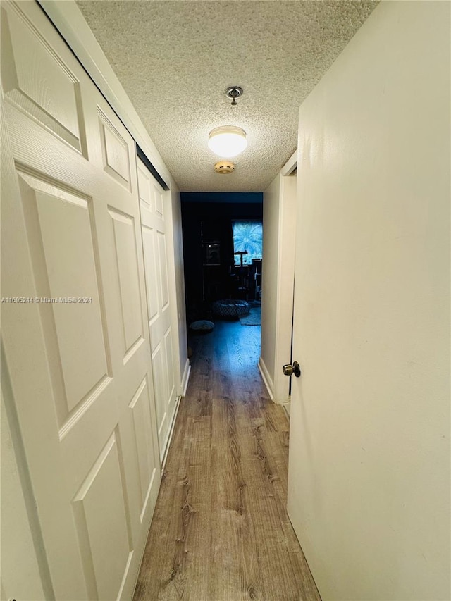 hall featuring a textured ceiling and hardwood / wood-style flooring