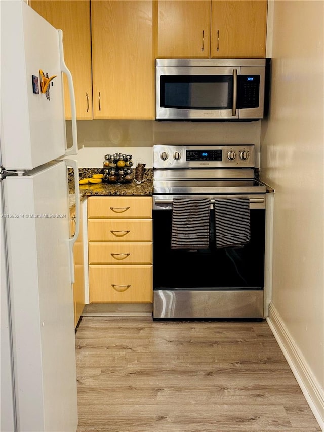 kitchen with dark stone countertops, light wood-type flooring, stainless steel appliances, and light brown cabinetry