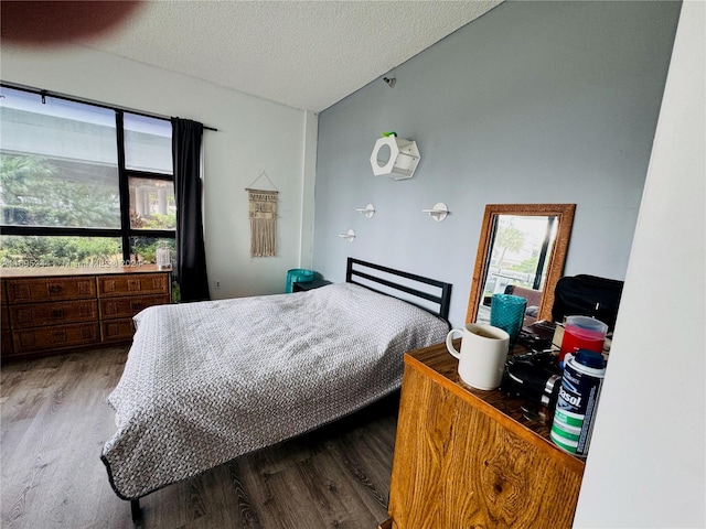 bedroom with a textured ceiling, light hardwood / wood-style floors, and multiple windows