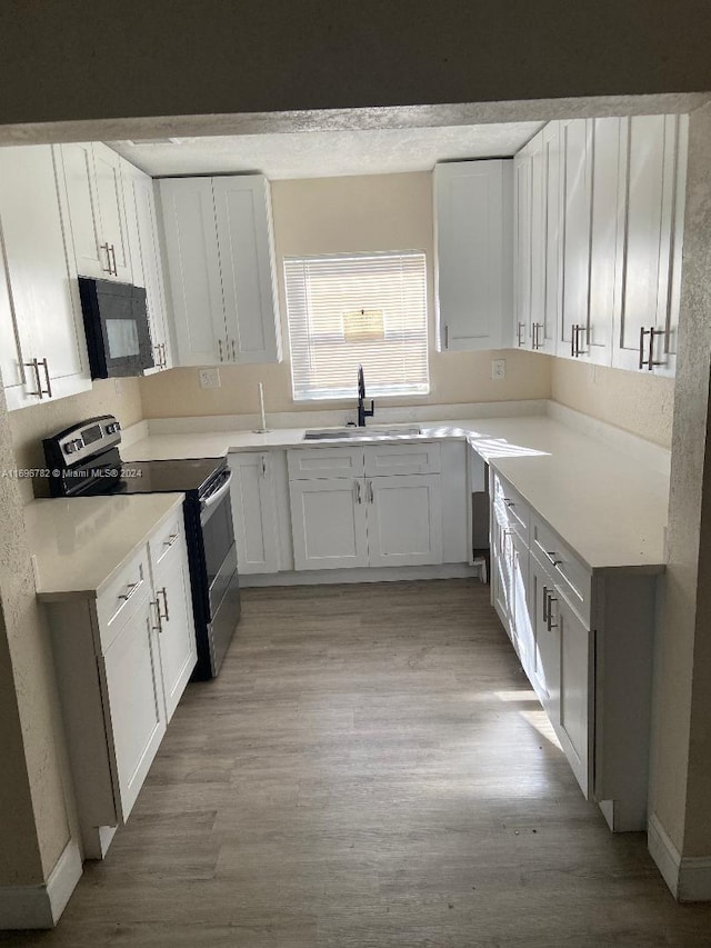 kitchen with white cabinets, light wood-type flooring, stainless steel electric range oven, and sink