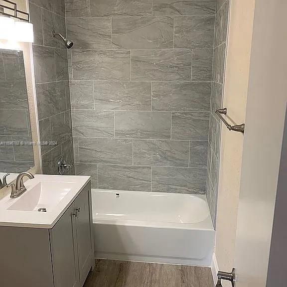 bathroom with vanity, hardwood / wood-style flooring, and tiled shower / bath