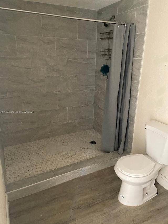 bathroom with hardwood / wood-style floors, toilet, and walk in shower