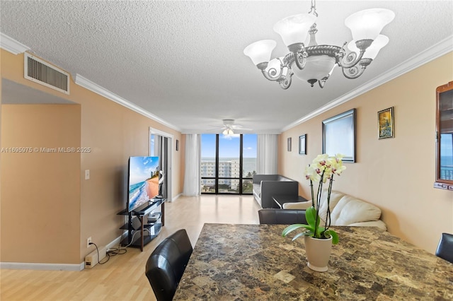 dining area featuring crown molding, ceiling fan with notable chandelier, and expansive windows