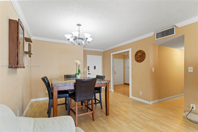 dining space with a notable chandelier, ornamental molding, and hardwood / wood-style flooring