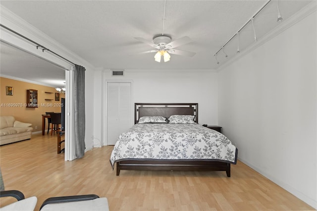 bedroom featuring ceiling fan, a textured ceiling, ornamental molding, and hardwood / wood-style flooring