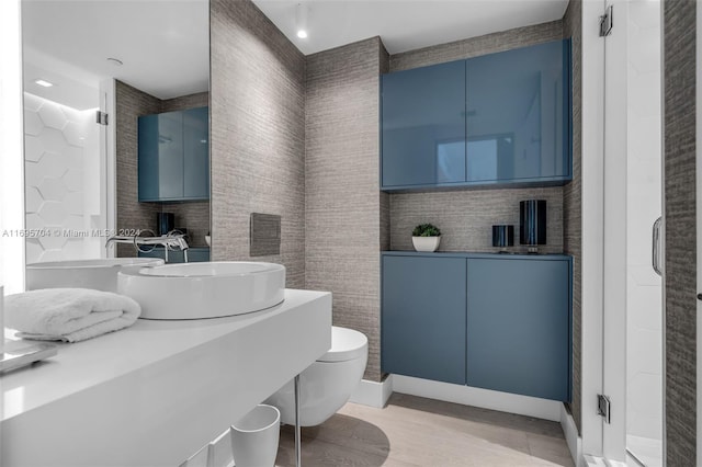 bathroom with vanity, a shower with door, wood-type flooring, tile walls, and toilet