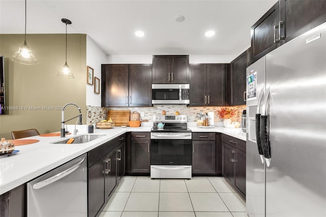 kitchen featuring sink, light tile patterned floors, backsplash, stainless steel appliances, and decorative light fixtures