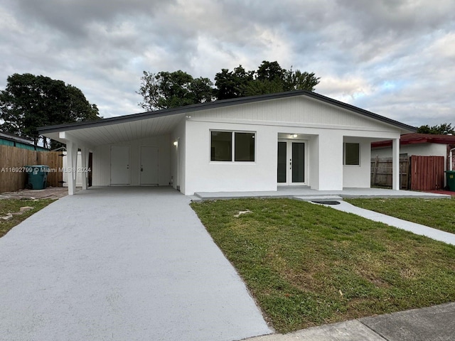 view of front of home with a carport, a front yard, and french doors