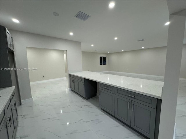 kitchen with gray cabinetry and light stone counters