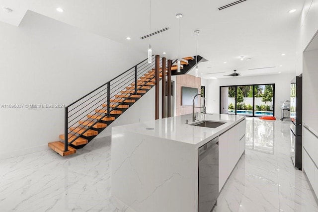 kitchen featuring ceiling fan, sink, pendant lighting, a center island with sink, and white cabinets