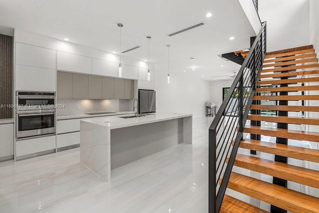 kitchen featuring tasteful backsplash, stainless steel appliances, sink, decorative light fixtures, and gray cabinets