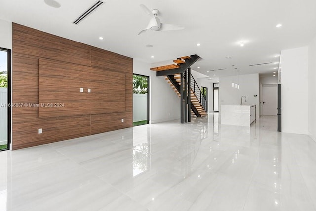 interior space with ceiling fan and wooden walls