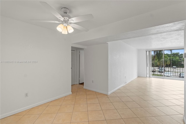 unfurnished room featuring ceiling fan, light tile patterned floors, and a textured ceiling