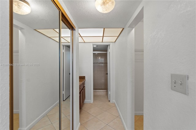 7100 NW 17th St Unit 219, Plantation, FL 33313 - hallway featuring light tile patterned floors, a textured ceiling, baseboards, and a textured wall