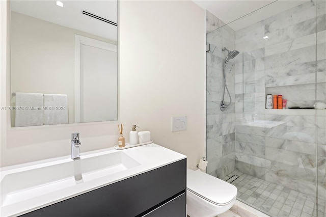 bathroom featuring vanity, toilet, and a tile shower