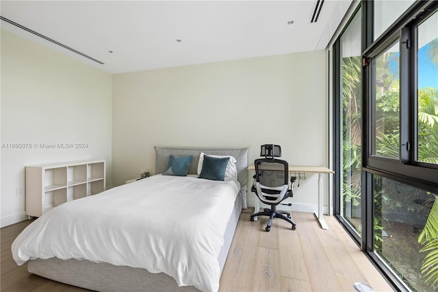 bedroom with expansive windows and light hardwood / wood-style floors