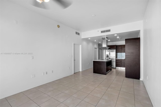 kitchen featuring visible vents, island exhaust hood, light countertops, light tile patterned floors, and dark brown cabinets