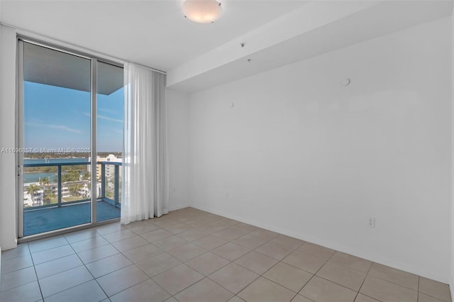 spare room with light tile patterned flooring and a wall of windows