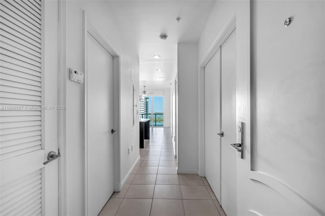 corridor featuring light tile patterned flooring and baseboards