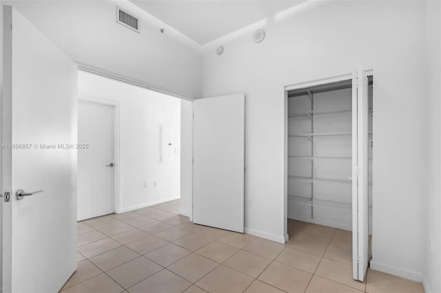 unfurnished bedroom featuring light tile patterned floors, visible vents, baseboards, and a closet