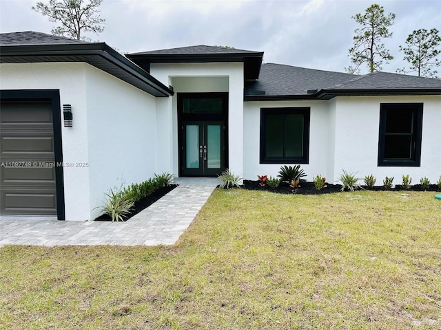 view of exterior entry with a lawn, french doors, and a garage