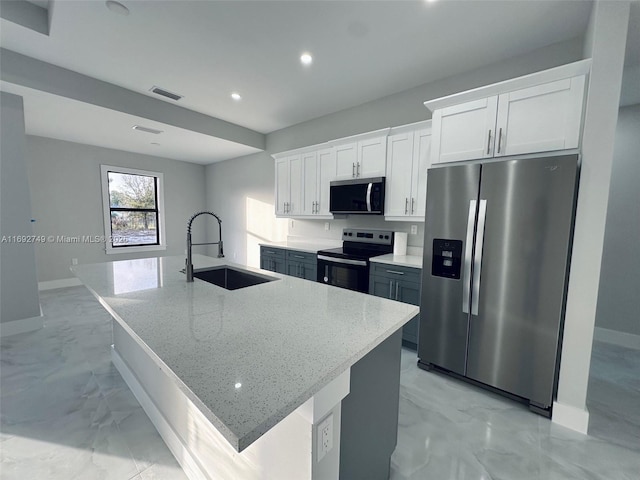 kitchen with white cabinets, stainless steel appliances, a kitchen island with sink, and sink