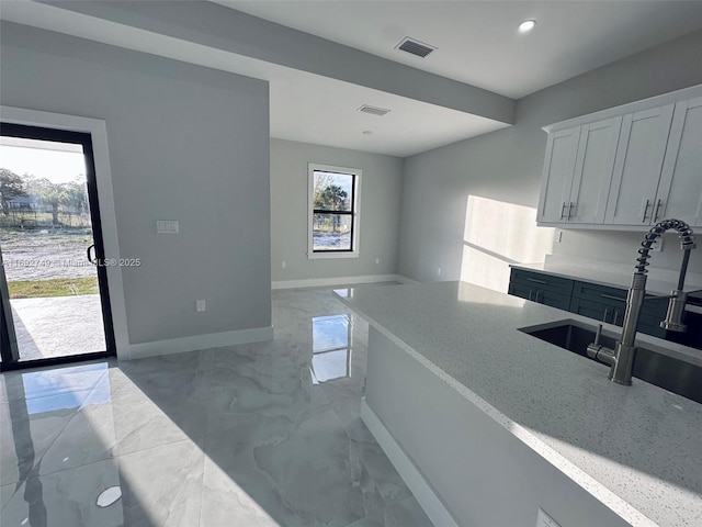 kitchen featuring white cabinets, light stone countertops, and sink