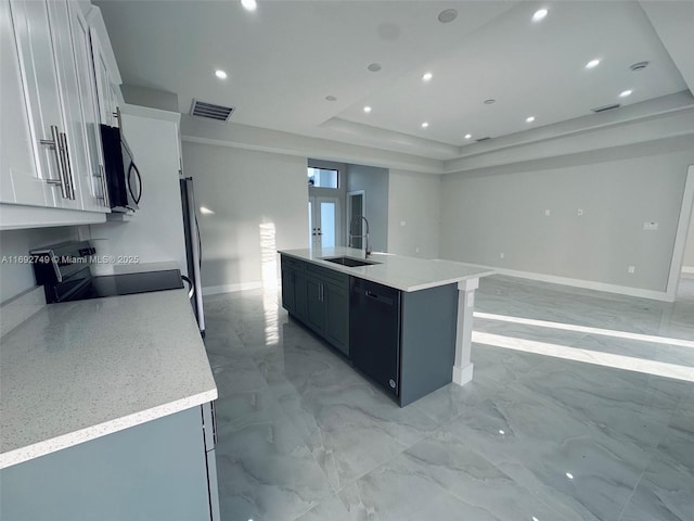 kitchen with white cabinetry, sink, a raised ceiling, a kitchen island with sink, and appliances with stainless steel finishes