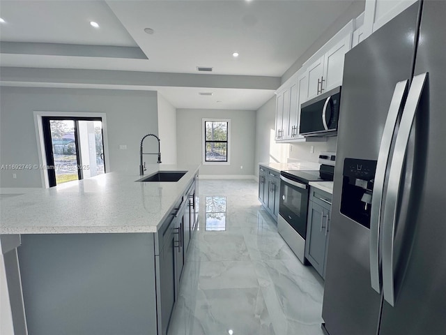 kitchen with appliances with stainless steel finishes, white cabinetry, a large island with sink, and sink