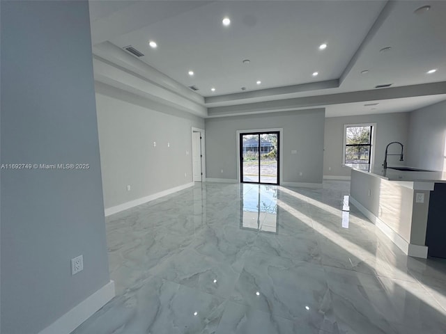 unfurnished living room with a raised ceiling and sink