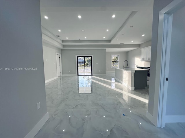 unfurnished living room featuring a raised ceiling and sink