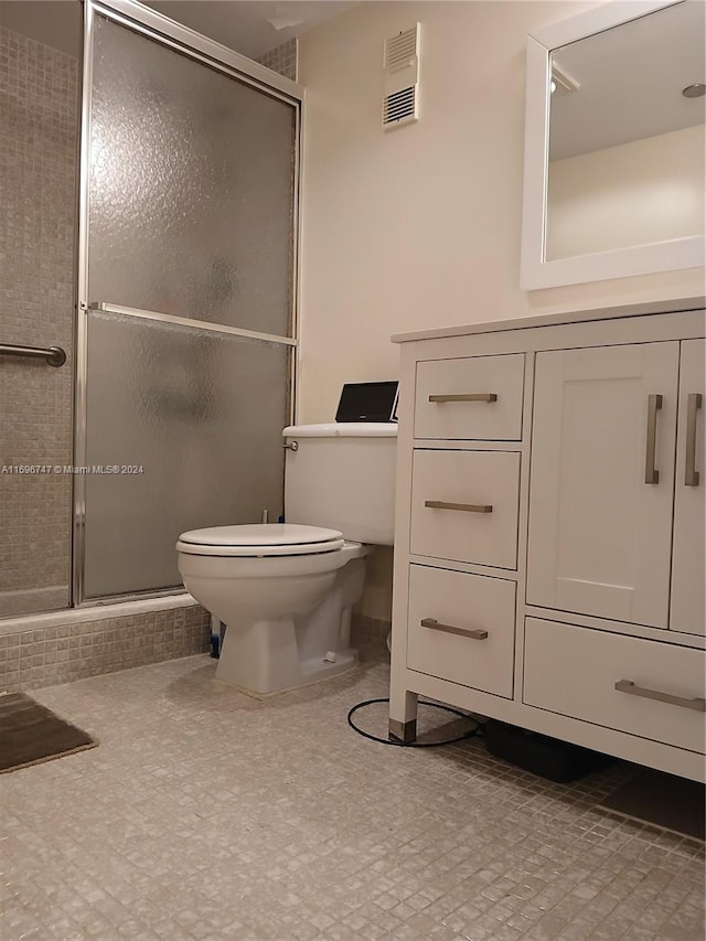 bathroom featuring vanity, toilet, and a shower with door