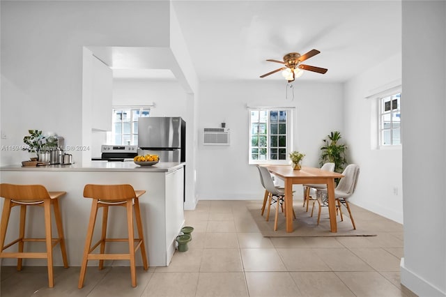 kitchen with a kitchen bar, electric range oven, stainless steel refrigerator, and a wealth of natural light